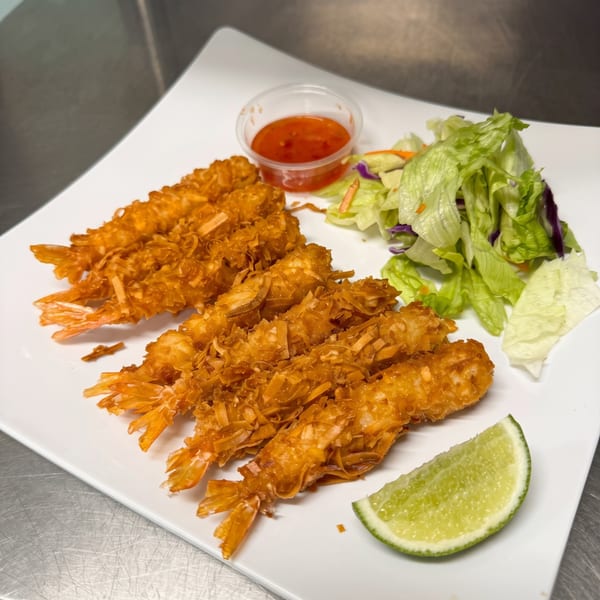 Crispy coconut shrimp with sweet chili sauce, a fresh side salad, and a lime wedge.